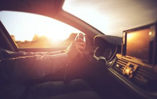A person driving a car with the sun in the background | Featured image for the blog Best Time of Year to Buy a Car from FinanceBeagle.